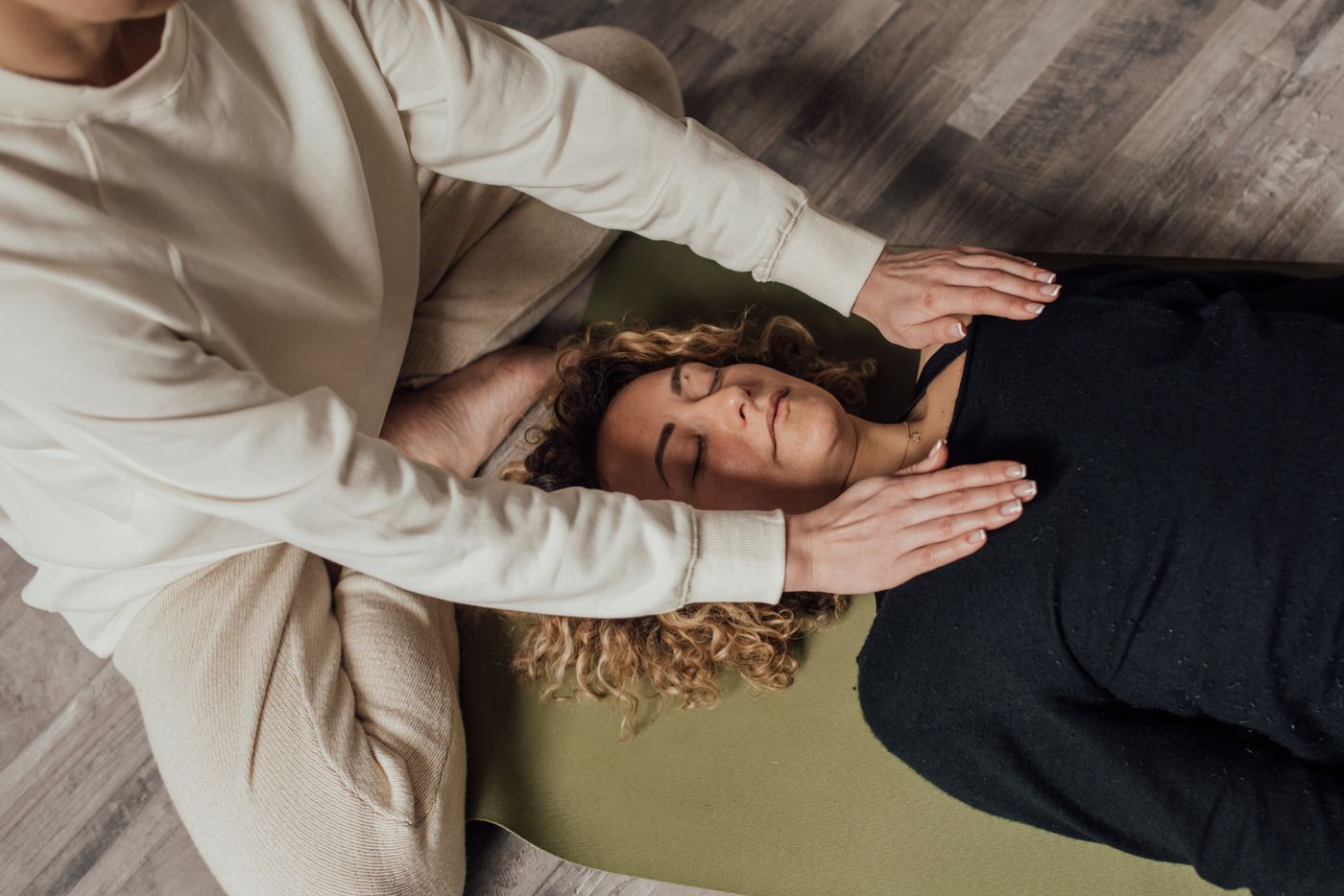 Sesión de Reiki vista desde arriba: manos de la practicante sobre una persona tumbada